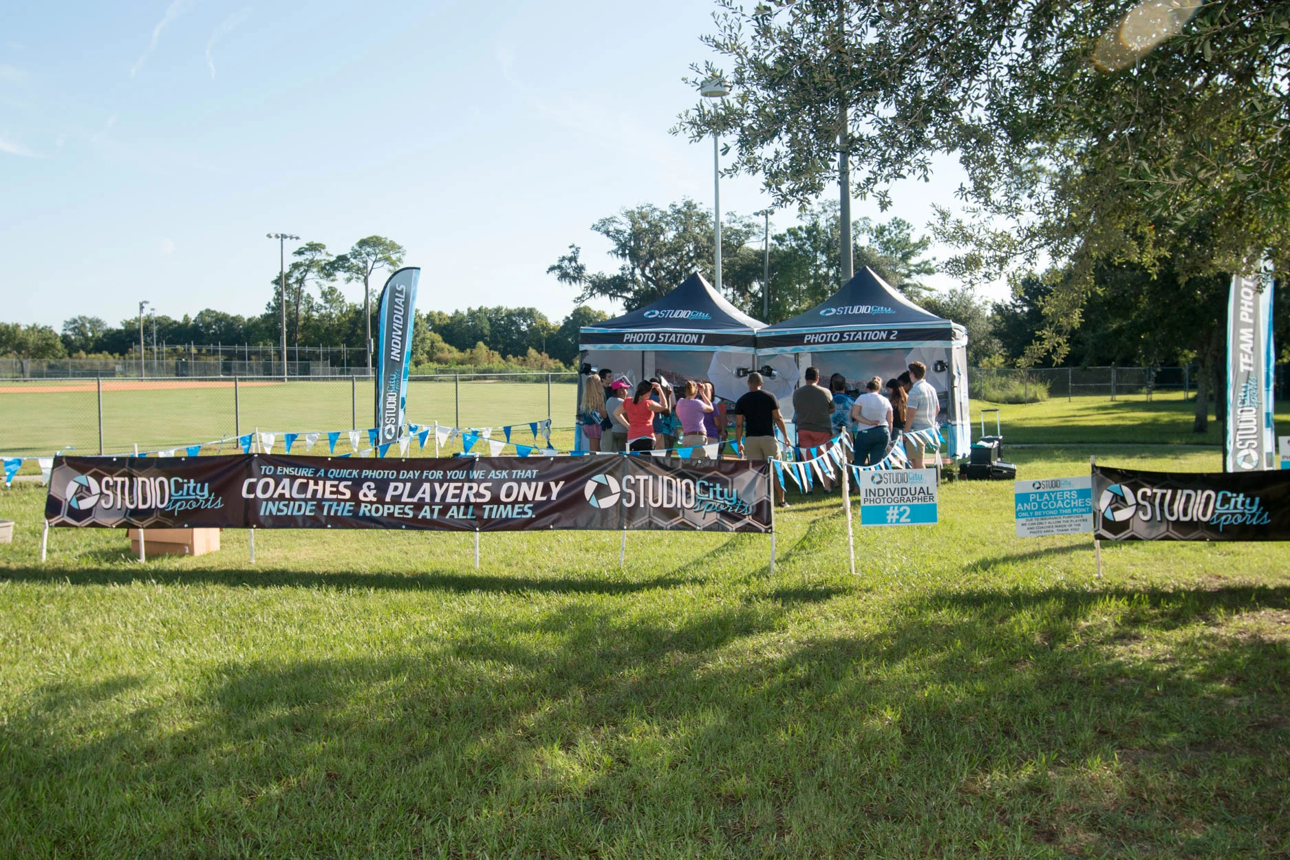 Photo Day Cashier Station Setup For Youth Sports Photography By Studio City Sports With Check-In Booth, Banners, And Outdoor Field.
