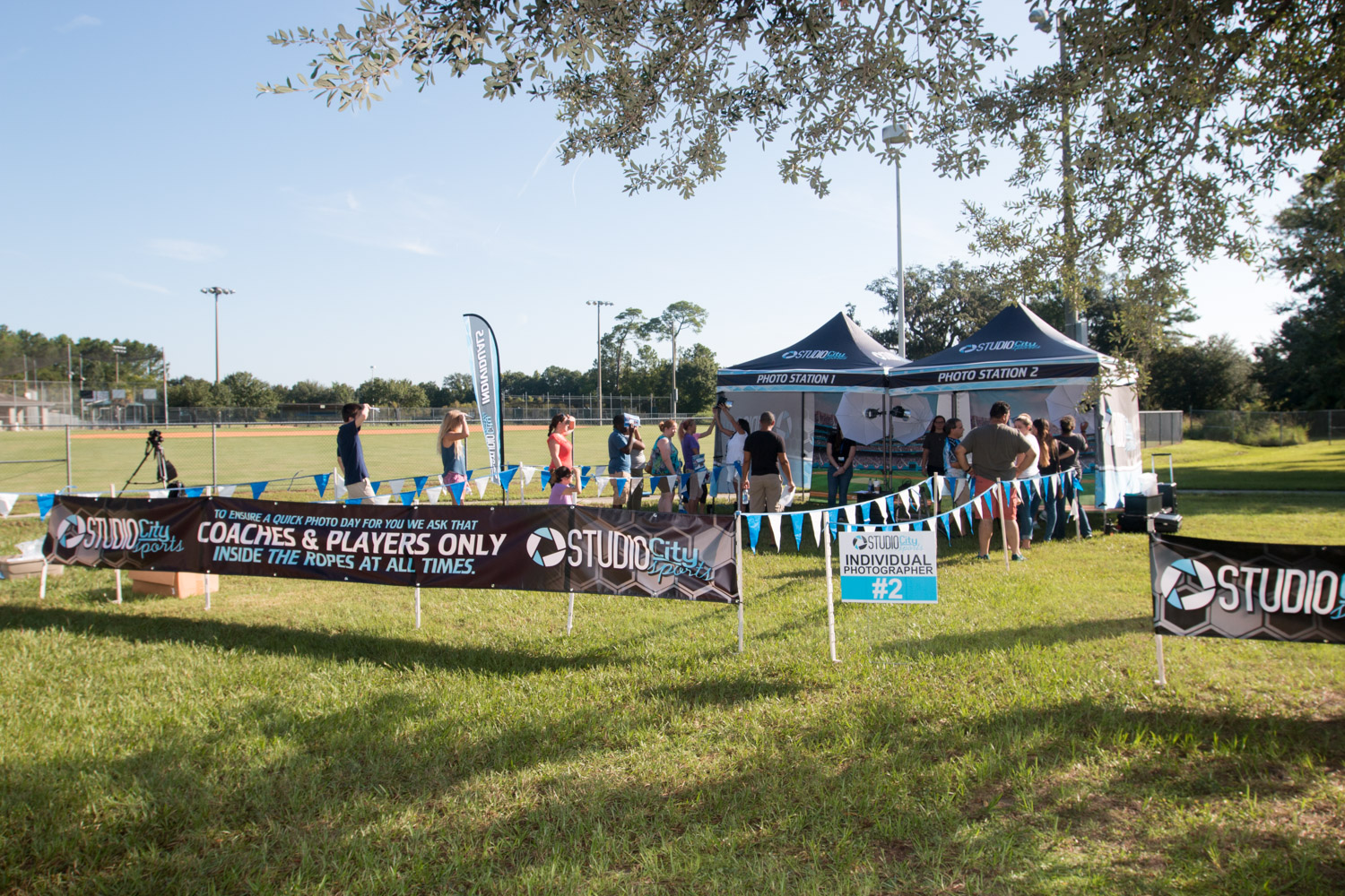 Well-Organized Youth League Picture Day With Check-In Table, Orderly Team Line, And Lit Backdrop